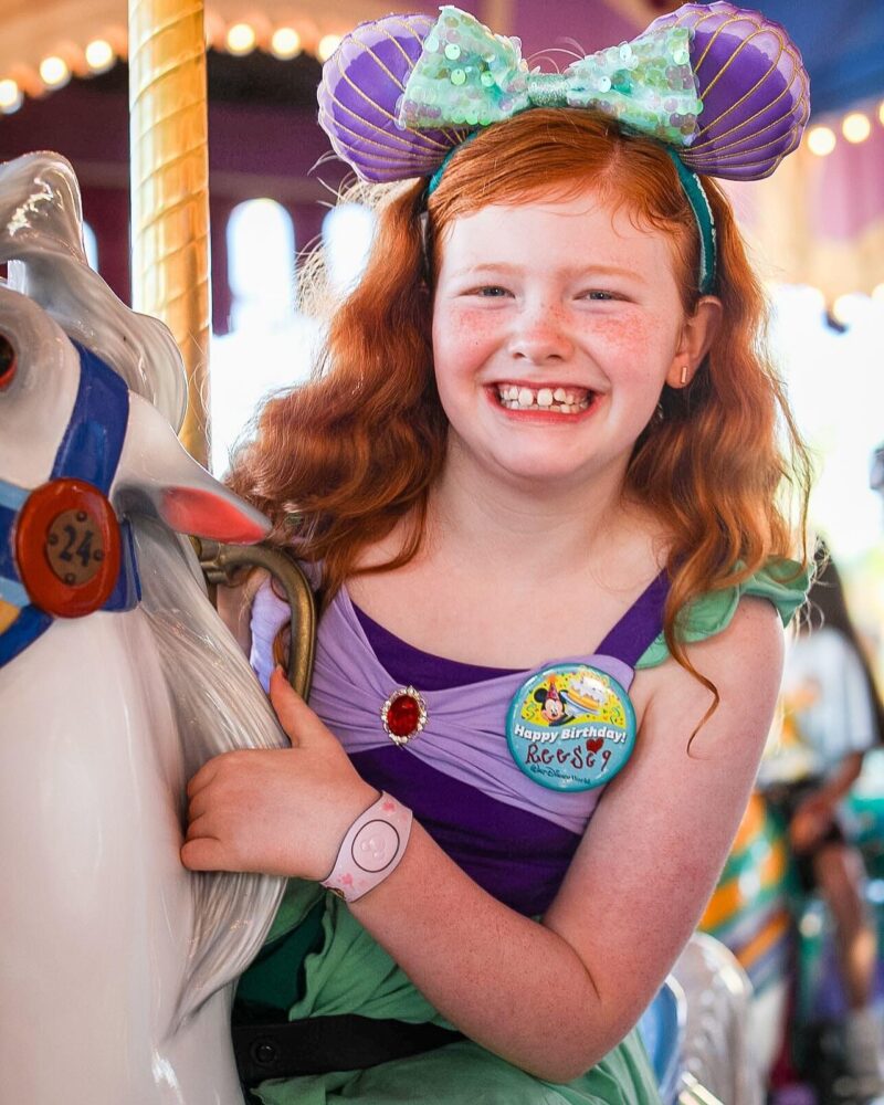 Travel with Carie - girl on carousel celebrating birthday at Walt Disney World